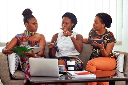 Three women collaborating around a laptop during a professional discussion